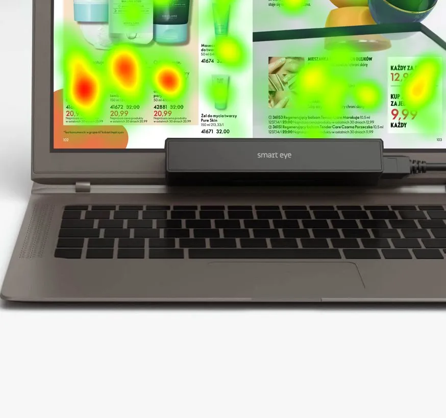Stanowisko badawcze: listwa eye trackera Smart Eye pod ekranem laptopa, na ekranie gazetka handlowa z nałożoną mapą cieplną